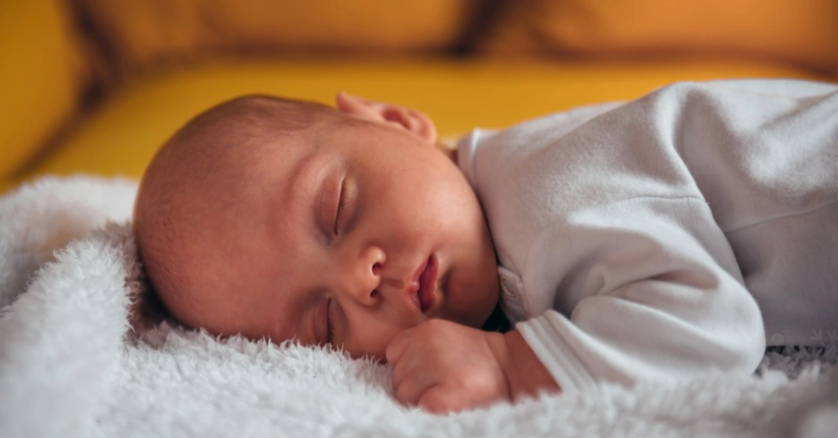 adorable baby boy sleeping on a yellow sofa at home